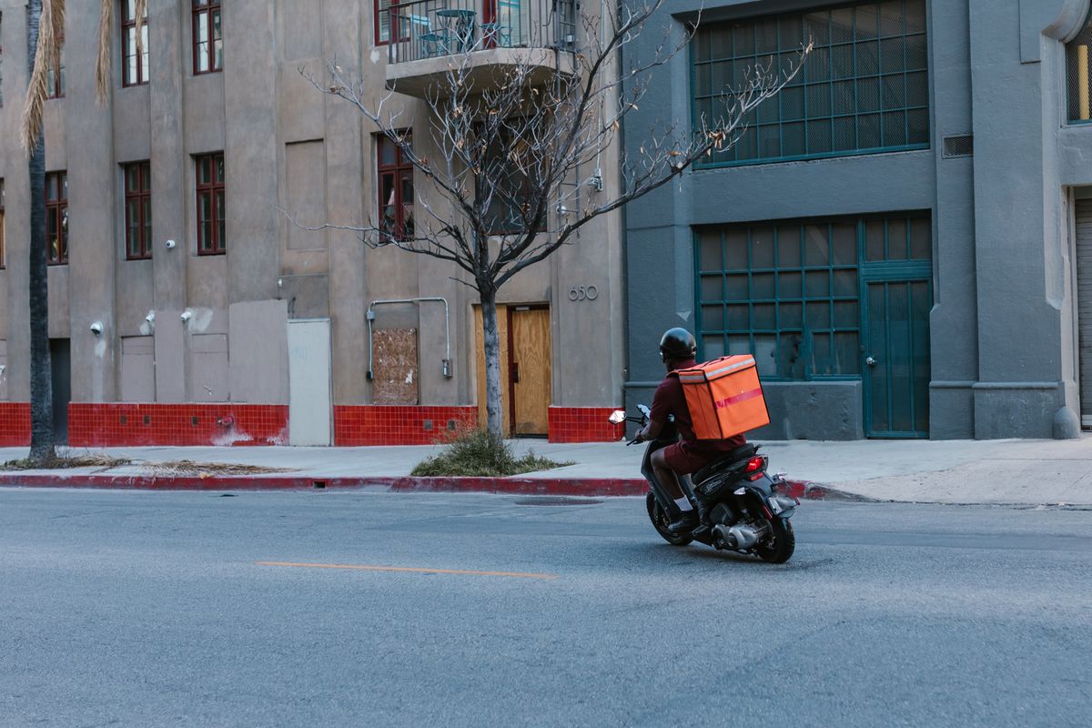 Mensajero en moto con caja de domicilio