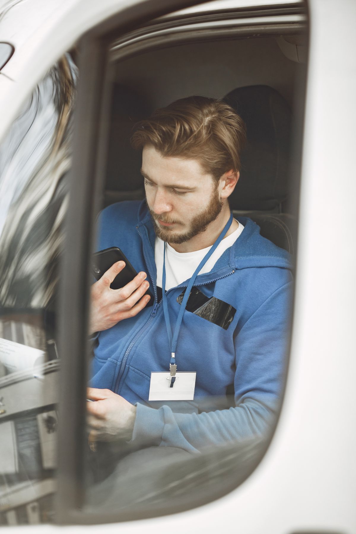 Mensajero revisando el celular dentro de un vehículo